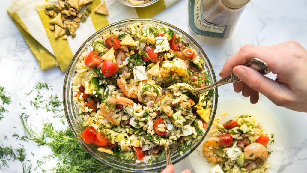 adding dressing to shrimp orzo salad